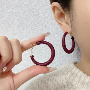Close-up view of retro burgundy leather wrapped hoop earrings worn by an Asian model