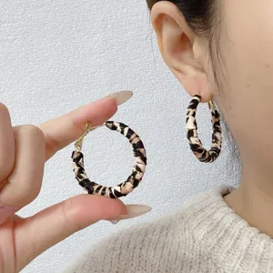 Detailed view of stylish retro leopard print leather hoop earrings worn by a model