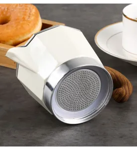 Close-up detail of the bottom stainless steel filter on a creamy white moka pot