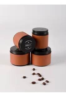 Vista detallada de los botes de café JOINOUT con fundas de cuero marrón y granos