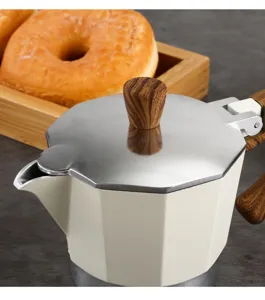 Close-up macro view of a cream Moka pot lid with wood-grain knob and metallic surface finish
