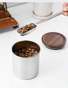 Detail van roestvrijstalen koffiebus met houten deksel en maatschepje voor bonen