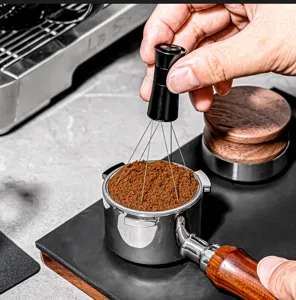 Primer plano de un distribuidor de café de agujas removiendo el café en el portafiltros