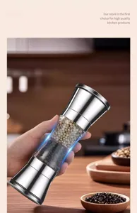 Hand holding a high-quality double-ended stainless steel manual spice grinder in a kitchen setting