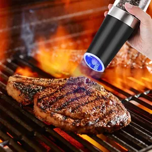Electric gravity pepper grinder seasoning steak on a grill with blue LED light