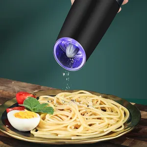 Detail of electric gravity pepper grinder with blue LED light grinding over a pasta plate