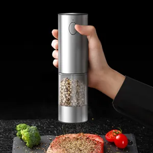 Elektrische Pfeffermühle aus Edelstahl würzt ein Steak auf einem Schieferbrett