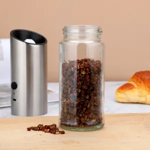 Detailed view of a clear glass spice jar and a stainless steel electric pepper grinder.