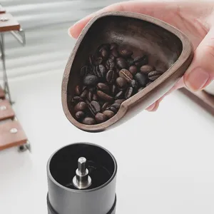 Bandeja triangular de madera oscura para granos de café vertiendo en un molinillo