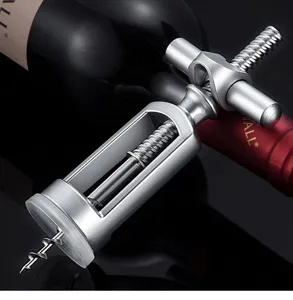 Macro view of a durable silver alloy manual wine corkscrew resting on a red wine bottle.
