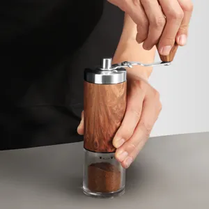 Handmatige koffiemolen met houtnerf body, handzwengel en doorzichtige houder voor verse koffie.