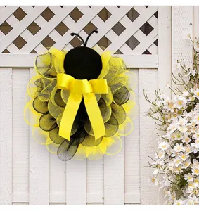Detalle de corona de malla de abeja, malla negra y amarilla con lazo para decoración de puerta.
