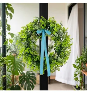 Detailed view of artificial green leaf wreath featuring a vibrant blue ribbon bow decoration