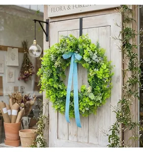 Detailed view of lush green artificial wreath featuring a long blue velvet ribbon.
