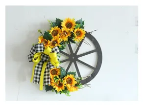 Detailansicht eines rustikalen Sonnenblumenkranzes mit karierter Schleife auf Holzrad