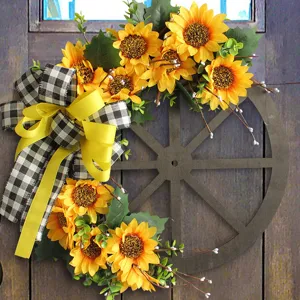 Sonnenblumenkranz mit karierter Schleife auf rustikalem Wagenrad für die Türdekoration.