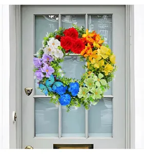 Colorful rainbow artificial flower wreath with butterfly detail on a grey front door