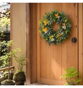 Vue détaillée d'une couronne de tulipes jaunes suspendue à une porte en bois au soleil.