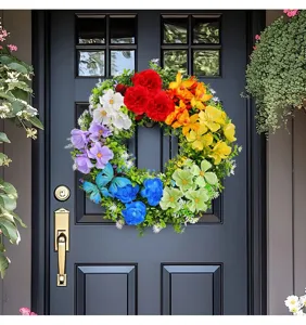 Close-up detail of a vibrant rainbow artificial flower wreath hanging on a dark front door