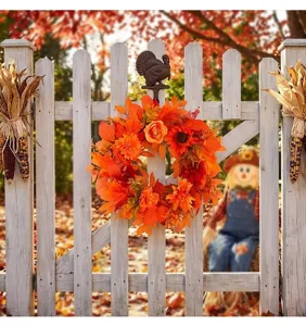 Close-up detail of autumn harvest wreath with orange maple leaves on white fence