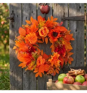 Detailed view of an autumn wreath with orange maple leaves and sunflowers on a rustic door