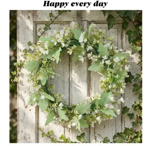 Détail d'une couronne de fleurs blanches et d'eucalyptus sur une porte en bois rustique