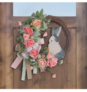 Beautiful Easter rabbit wreath with pink roses and ribbons hanging on a wooden door.
