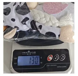 Detail view showing 130g weight of cow print faceless gnome doll on digital scale