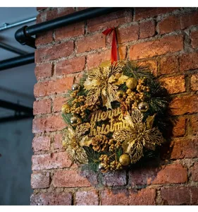 Detail of gold Christmas wreath with sequins and pinecones hanging on a brick wall