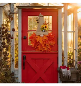 Ghirlanda di gnomo autunnale con barba di foglie d'acero e girasole su una porta rossa