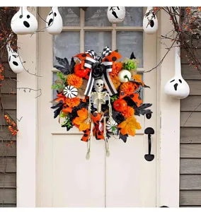 Halloween krans met skelet en pompoenen aan een witte vintage deur voor decoratie
