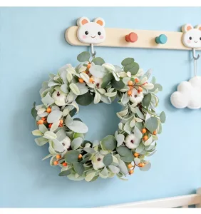 Decorative eucalyptus leaf wreath with white pumpkins hanging on a light blue wall