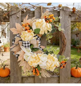 Artificial autumn decorative flower wreath with burlap bow and pumpkins for front door hanging.
