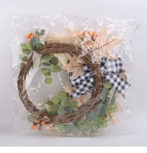 Detailed view of artificial autumn wreath with berries, maple leaves and plaid bow in bag