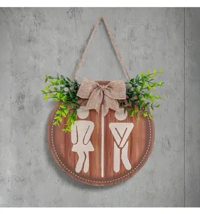 Detailansicht eines rustikalen runden Toilettenschilds aus Holz mit Juteschleife und Kunstgrün