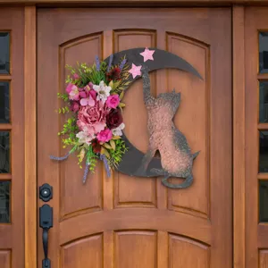 Detailed view of a floral crescent moon wreath with cat silhouette hanging on a brown wooden door