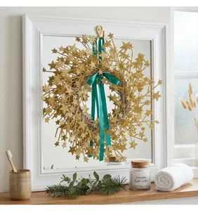 Gold glitter star wreath with a green ribbon displayed on a mirror for holiday decor