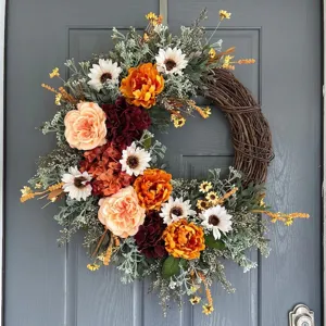 Vista dettagliata ghirlanda autunnale con rose arancioni e margherite su porta