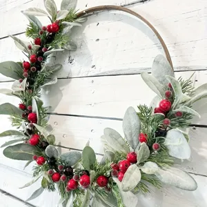 Gros plan d'une couronne de Noël avec baies rouges et feuilles d'oreille de lapin givrées.
