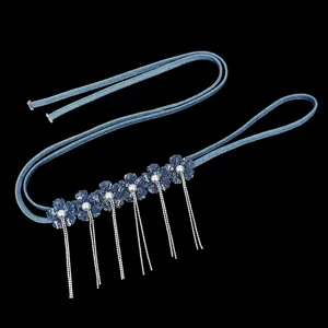 Cinturón de mezclilla con flores de tela, perlas y largas cadenas de flecos plateados.