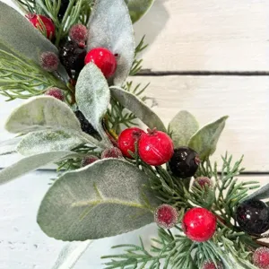 Gros plan de feuilles d'oreilles d'agneau givrées et baies rouges sur couronne