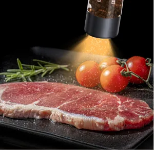 Nahaufnahme des tragbaren elektrischen Mahlwerks beim Würzen eines saftigen Steaks