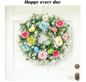 Detailansicht eines Osterkranzes mit bunten Eiern und Blumen an einer weißen Tür