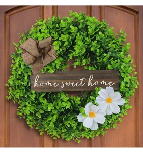 Macro detail of artificial eucalyptus wreath with white flowers and home sweet home sign on wood