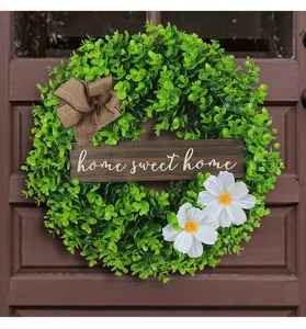 Macro view of artificial eucalyptus wreath with wooden home sweet home sign and white flowers