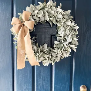 Artificial lamb's ear wreath with burlap bow hanging on a dark blue door for home decor