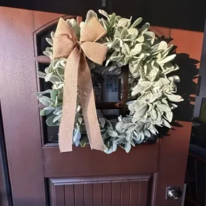 Detail view of spring artificial lamb's ear wreath with burlap bow on a wooden door
