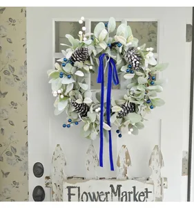 Artificial lamb's ear wreath with blue velvet ribbon and frosted pinecones for home decor.