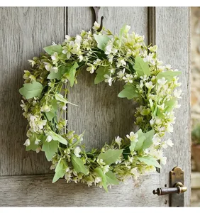 Couronne de fleurs printanière décorative avec petites fleurs blanches sur une porte en bois