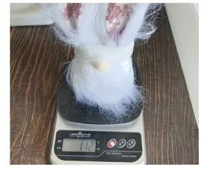 Weight measurement of a white Easter gnome doll with rabbit ears weighing 112 grams